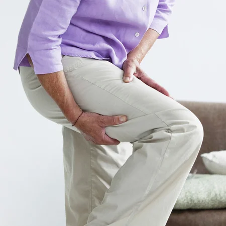 A woman holding her leg, experiencing sciatica pain