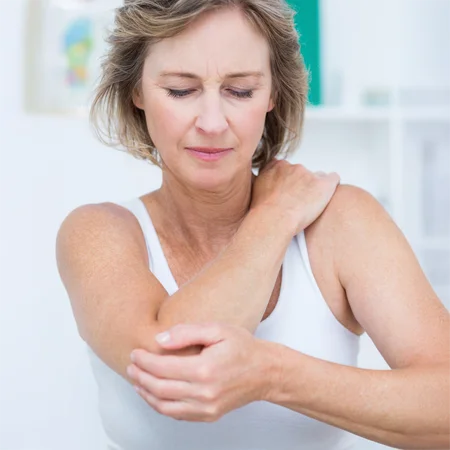 A woman holding her shoulder and elbow in pain