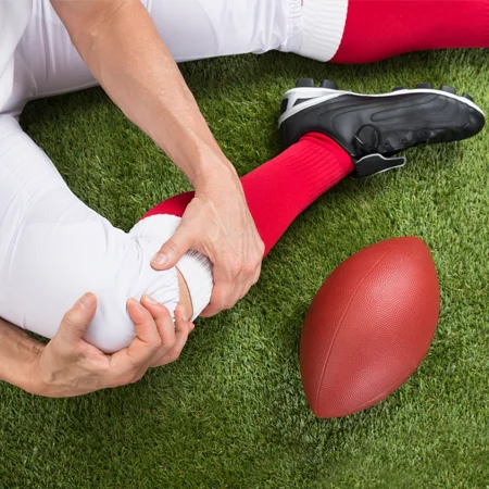 A football player on the ground, holding their knee after an injury