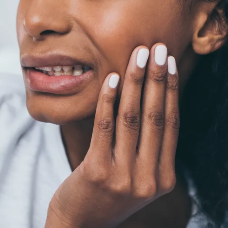 A woman holding her jaw in pain from TMJD